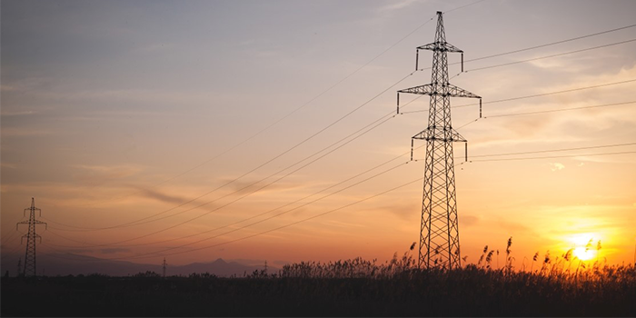 Luftburen elnätsledning i solnedgång.