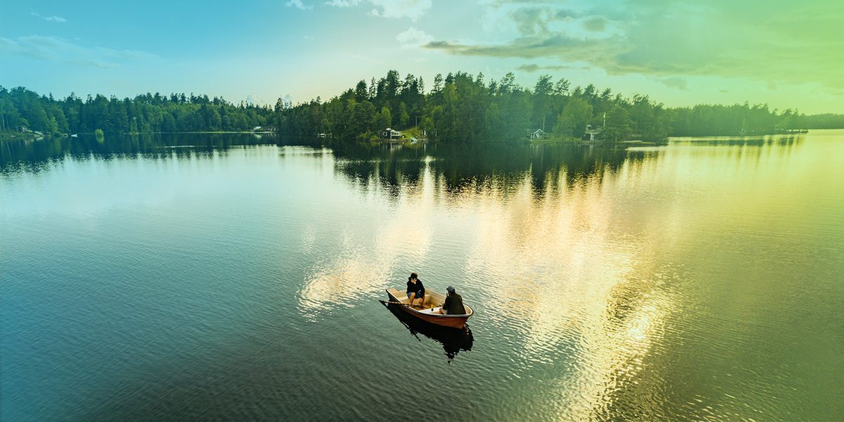 En drönarbild på en liten fiskebåt i en stor sjö omgiven av skog.