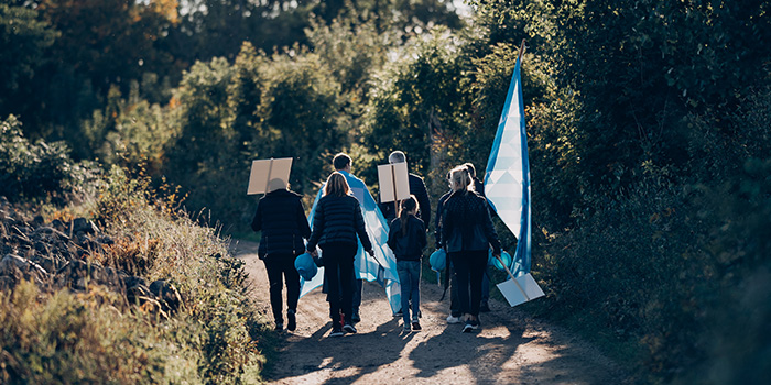 Ett gäng svartklädda människor som går på en grusväg på landet.