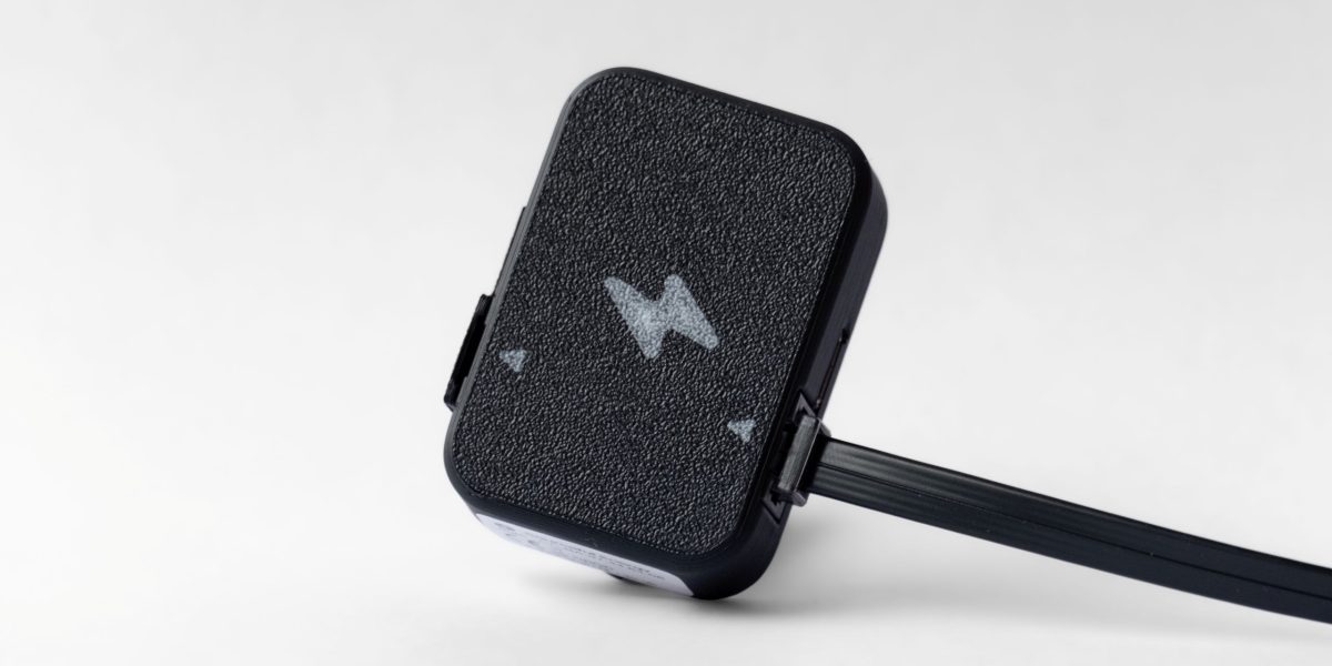 Realtidsmätare från Kalmar Energi fotograferad i studio på ljus bakgrund, med tydlig textur och svart kabel synlig på sidan.