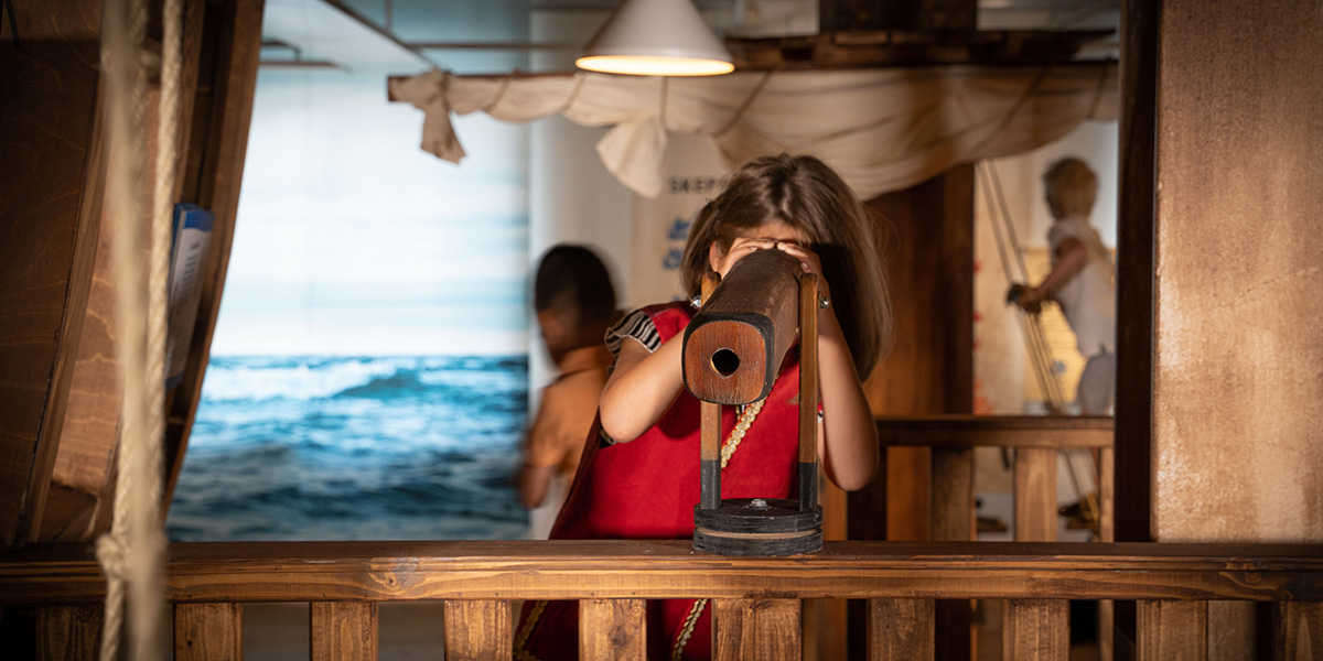 Flicka som är besökare på Kalmar läns museum som står uppe på Superkronan och tittar i en kikare.