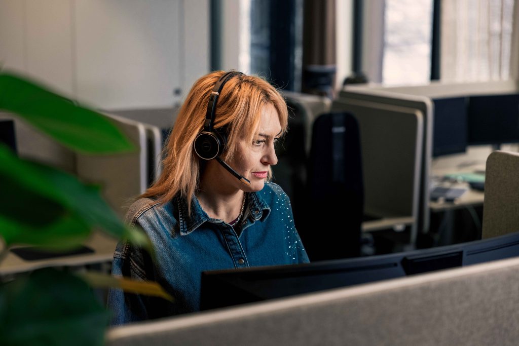 Medarbetare i Kalmar Energis kundcenter som arbetar vid dator med headset.