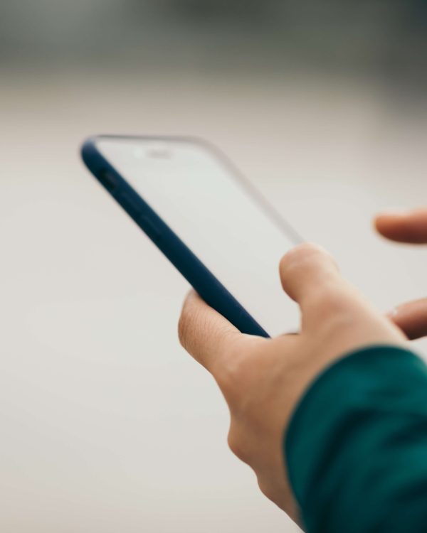 Händer som använder en smartphone mot ljus bakgrund.