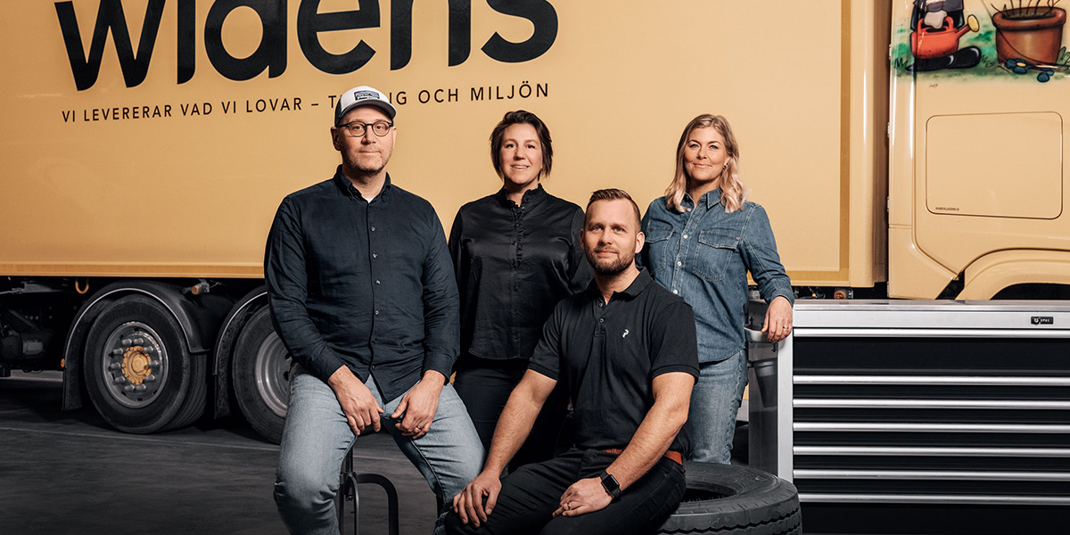 En gruppbild med medarbetare från Widéns Åkeri placerade framför en av deras lastbilar.